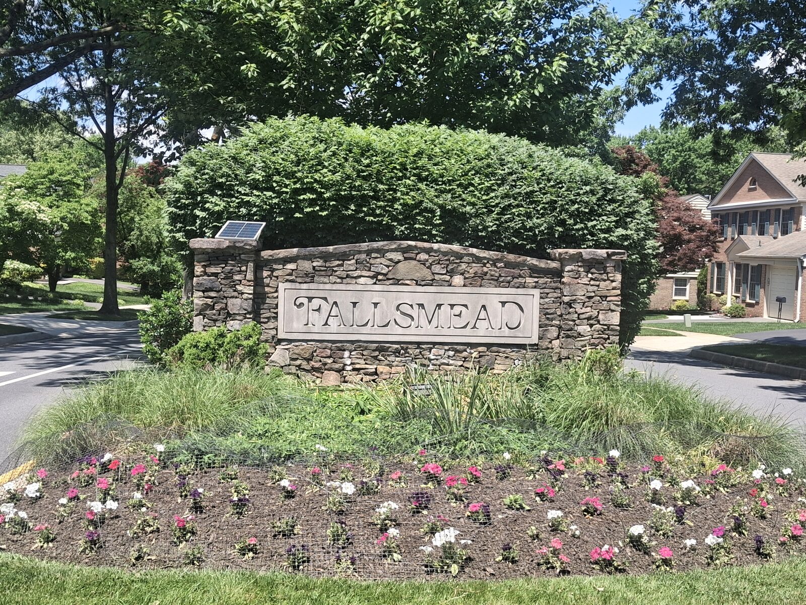 Stone "Fallsmead" community entrance monument with a flower bed in Rockville, MD