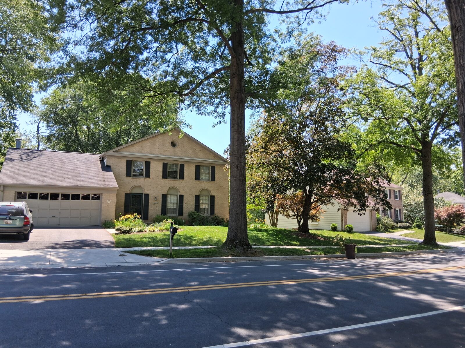 Two-story colonial home framed by mature trees on Greenplace Terrace in Fallsmead