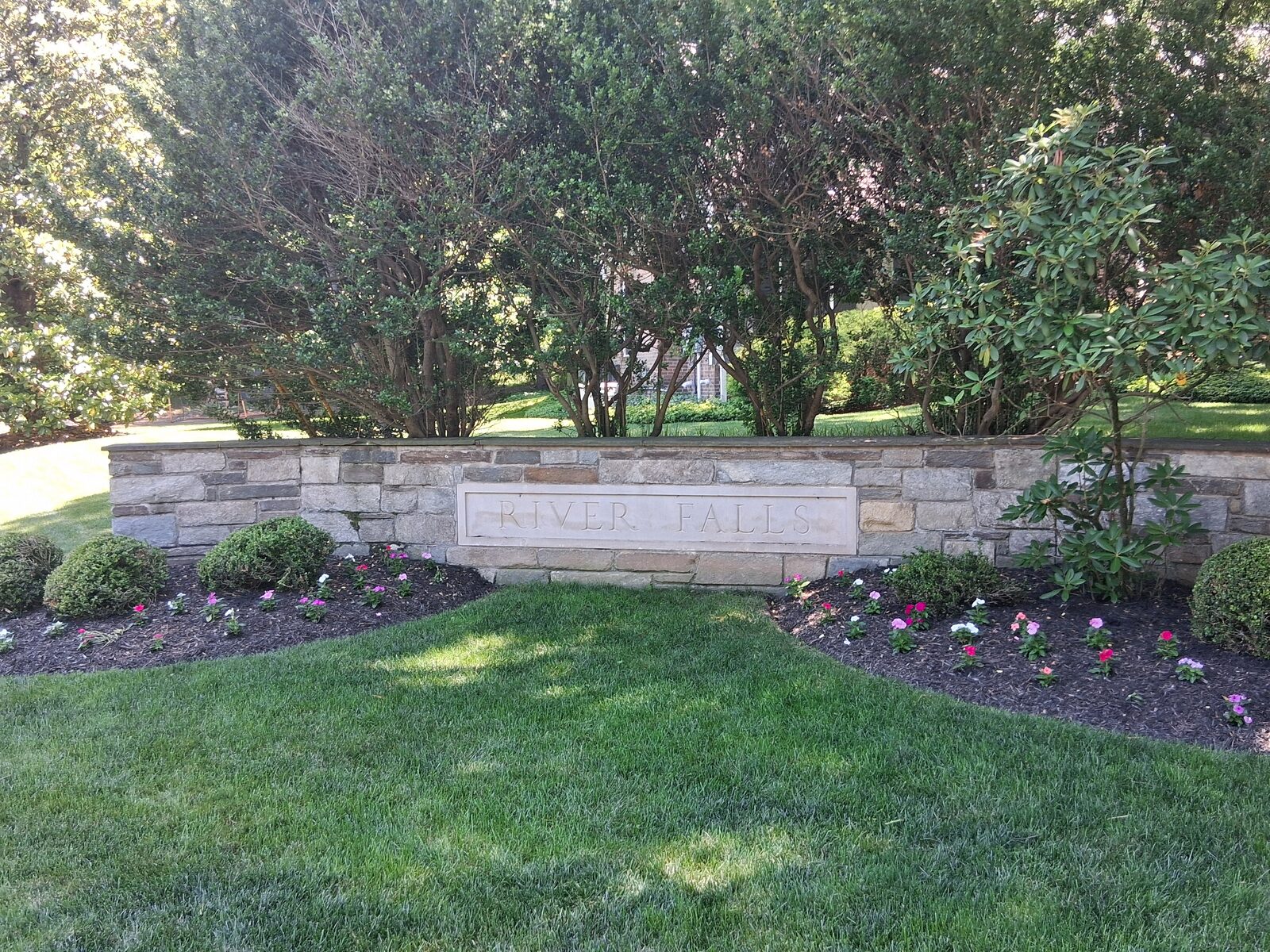 Stone River Falls entrance monument with landscaped flower beds in River Falls, Potomac